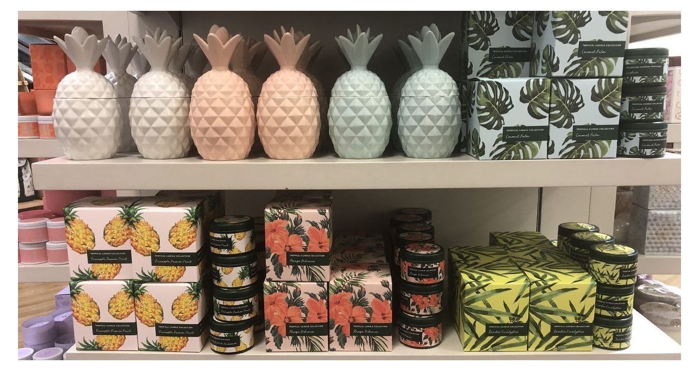 Different custom candle boxes stacked on two bookstore shelfs, one above the other. 