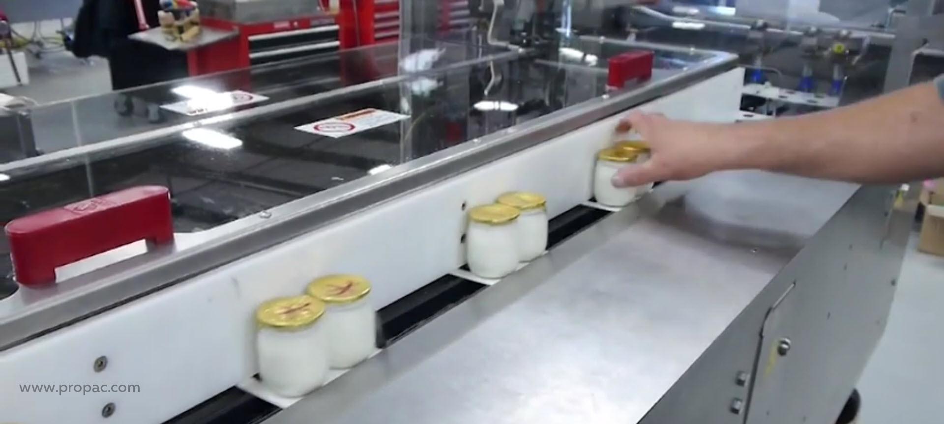 Manual placement of jars onto the paper packaging on a semi-automated cartoning machine.