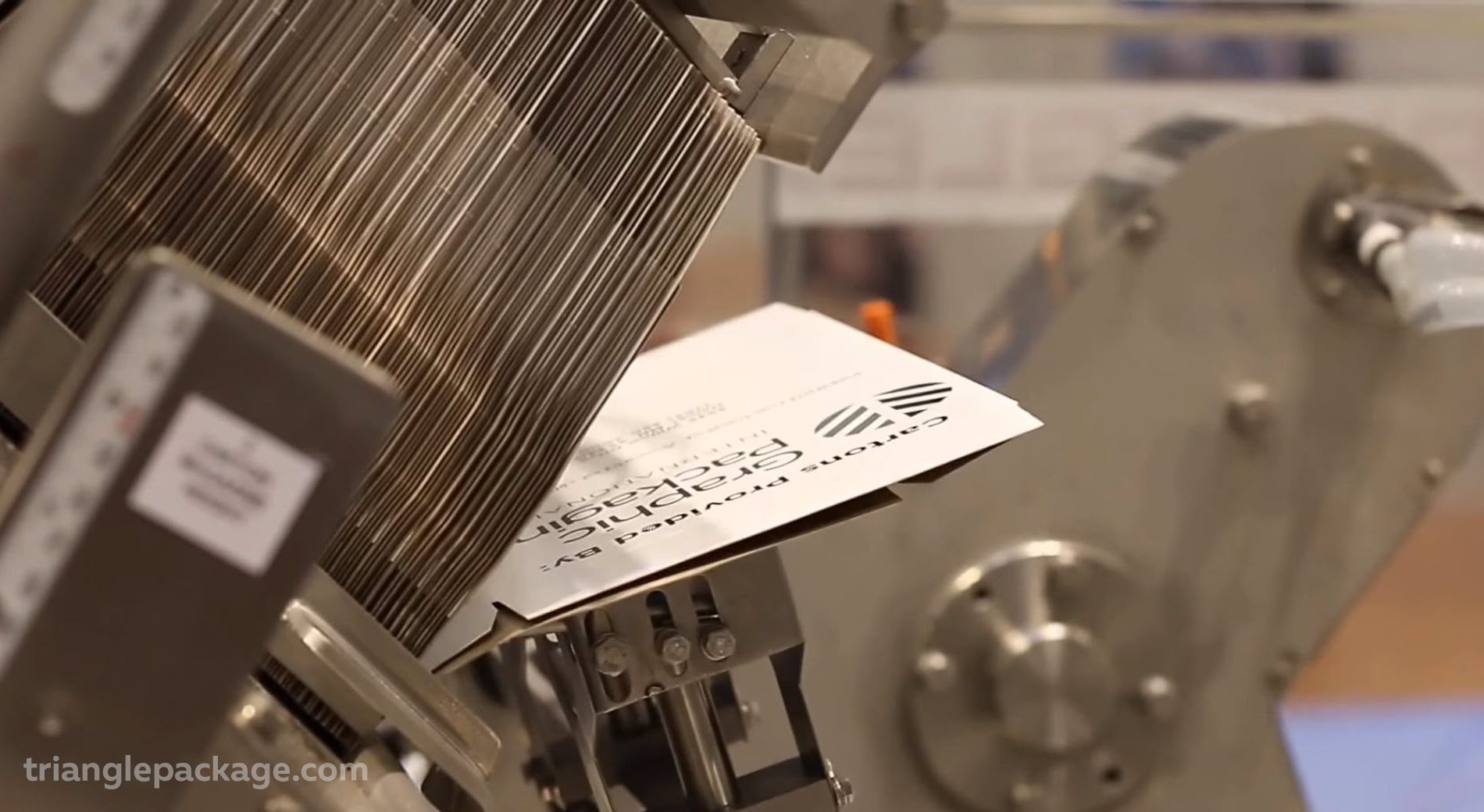 A stack of flat packaging boxes on a box erector system of an automated cartoning machine.