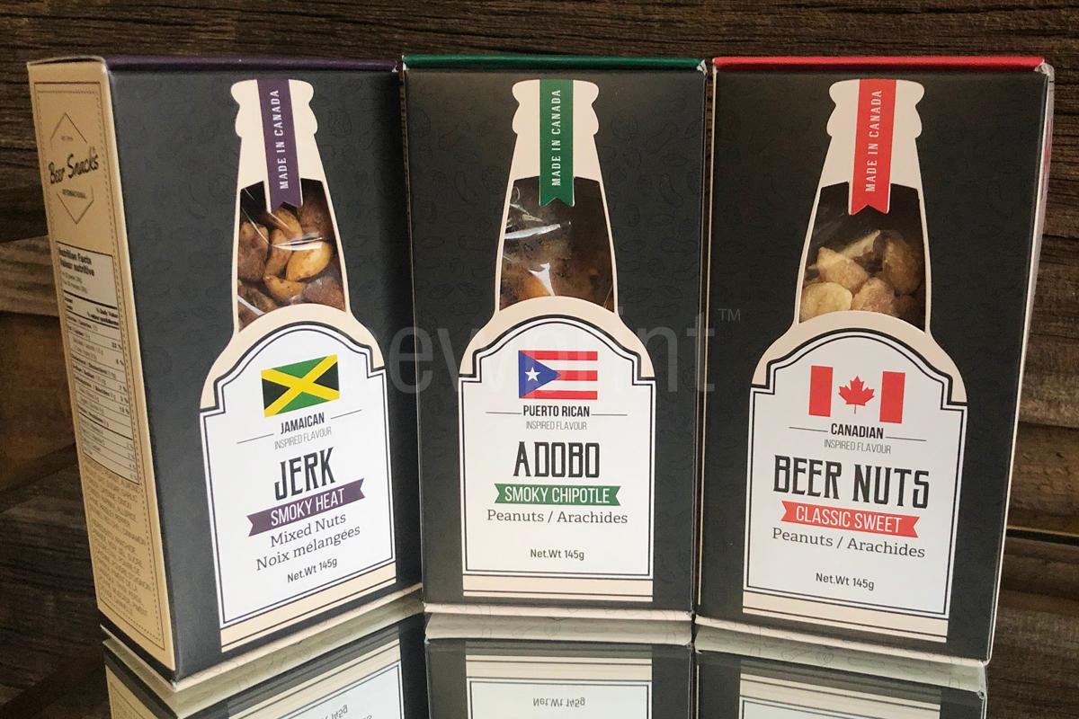 Three custom food packaging boxes containing nuts and snacks against a wooden background.