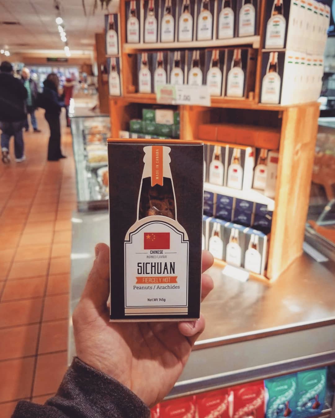 A hand holding a nuts custom food packaging box inside a store.