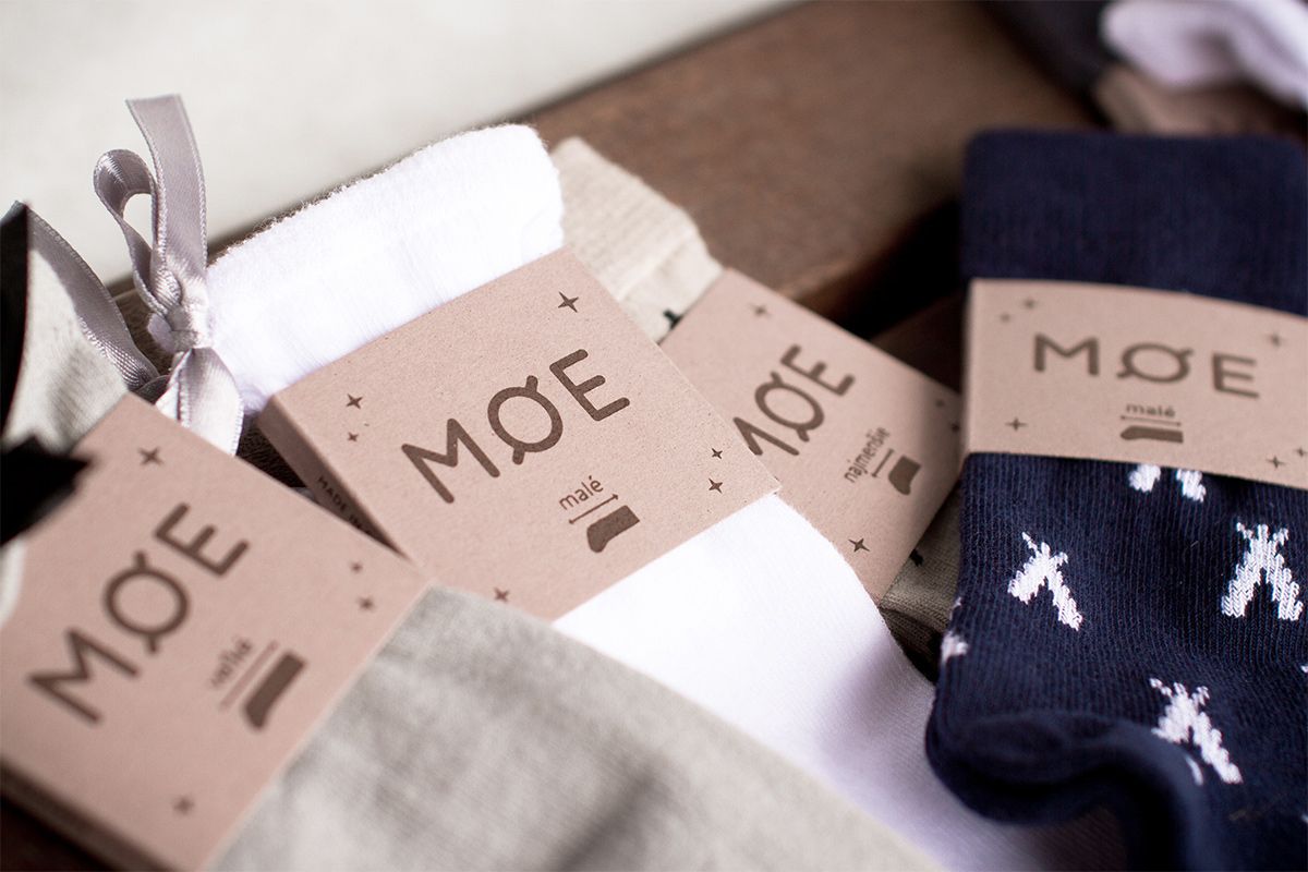 Four pairs of socks each with a paper sleeve wrapped around them with a clothing packaging design applied.