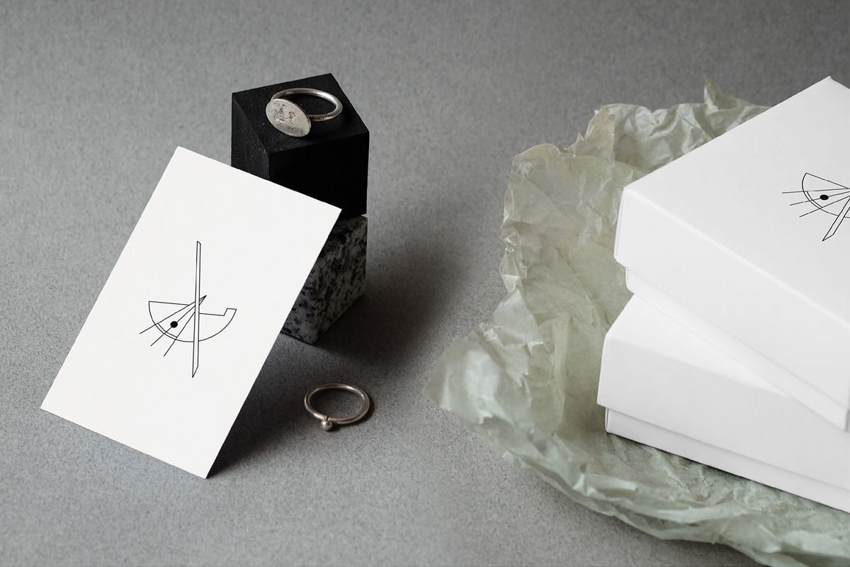 Jewelry Packaging Ideas-Two jewelry packaging boxes placed on tissue paper, with two rings and a business card next to them