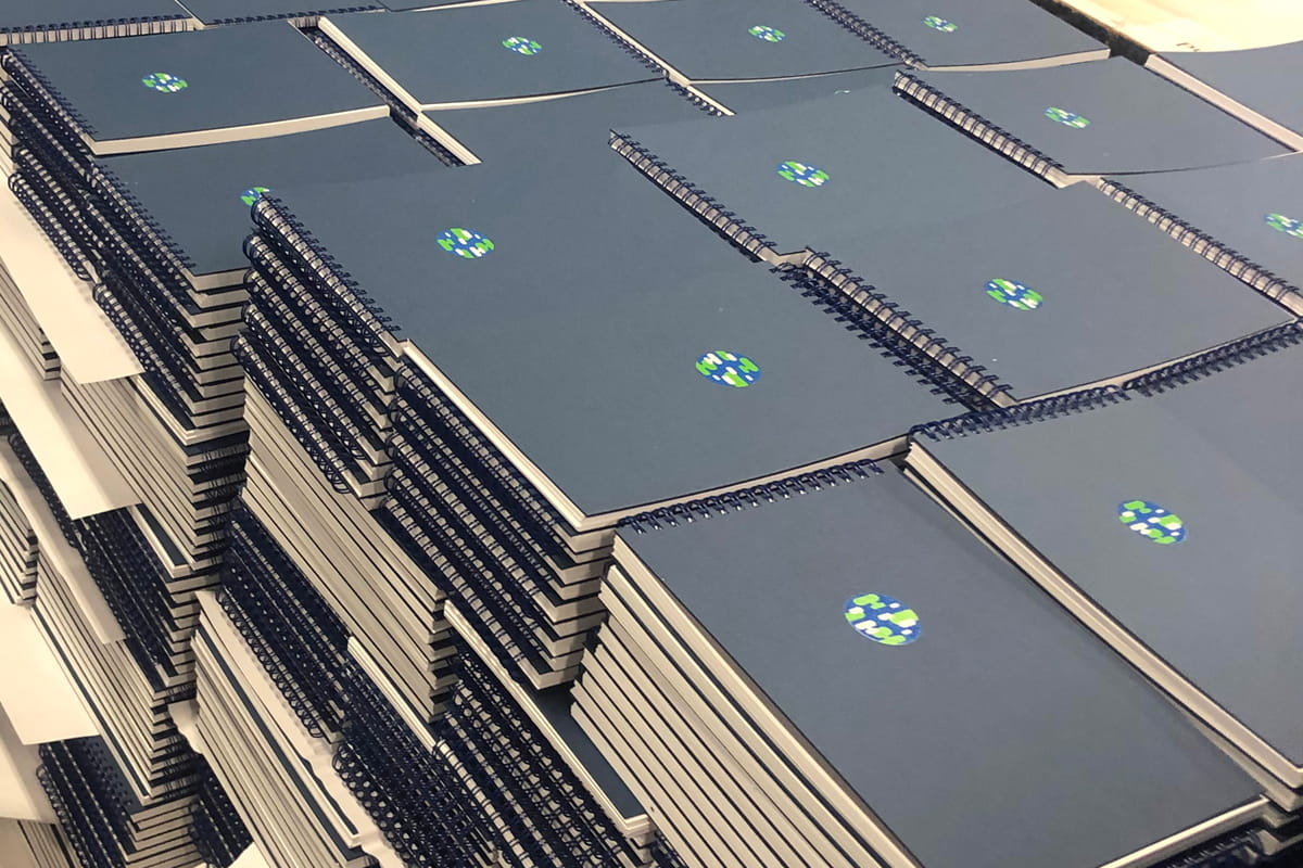 A stack of printed books at Newprint, featuring wire-o binding.