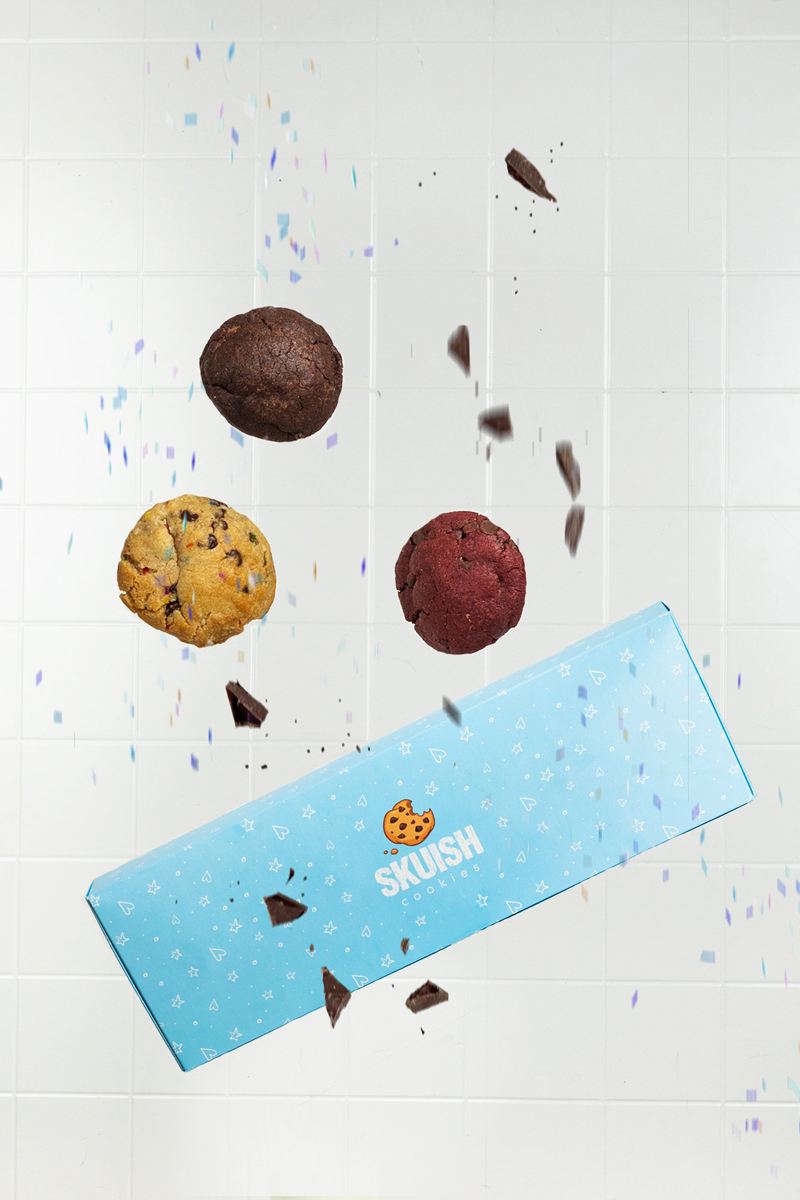 closed Skuish blue custom cookie boxes with cookies around it