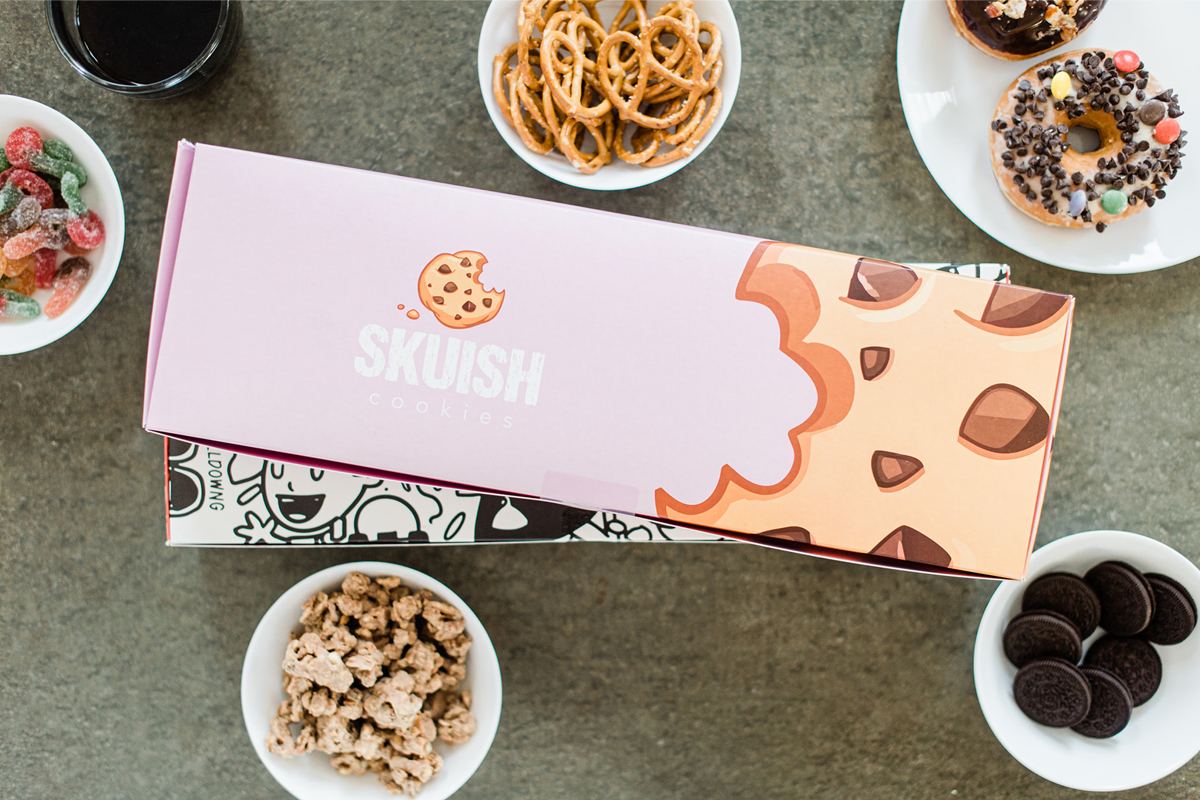 Two custom cookie box packaging boxes on the table with snacks around them