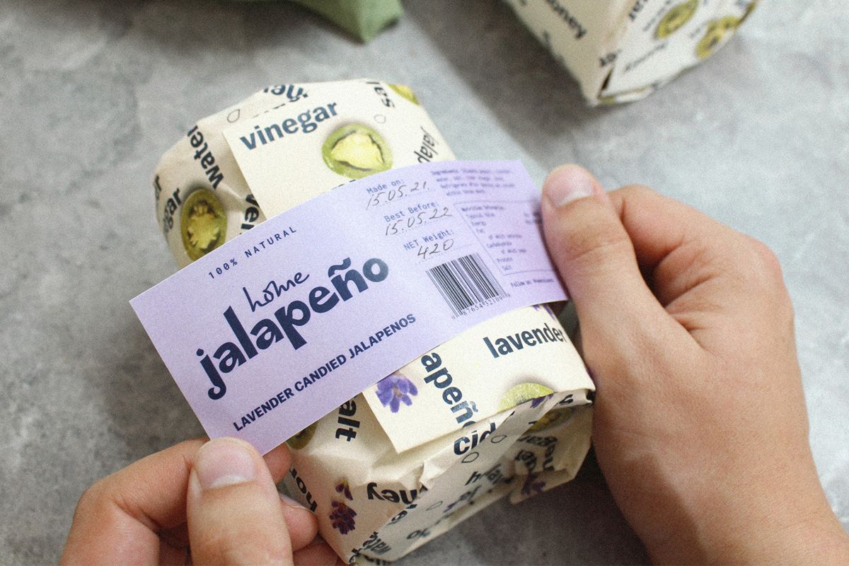 hands putting belly band on a jalapeno packaging with sustainable packaging design