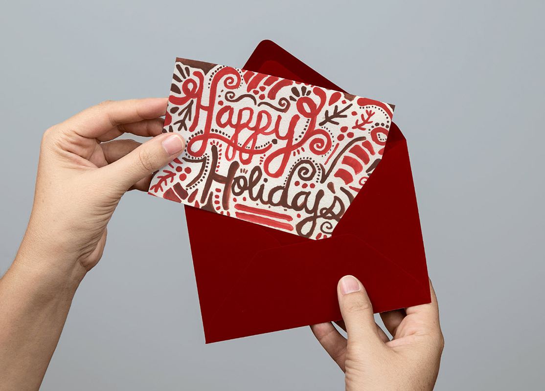 Christmas packaging design inspiration, hands holding a red envelope, and a holiday postcard.