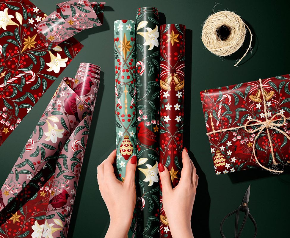 Christmas packaging design inspiration, hands holding three rolls of Christmas wrapping paper.