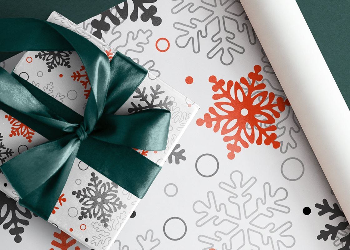 Christmas packaging design inspiration, a roll of wrapping paper with a wrapped present on top of it.