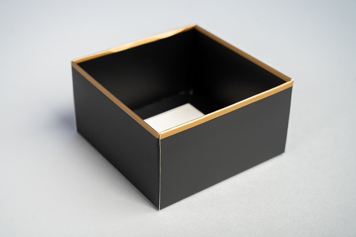 Image showing black base of two piece box with gold stripe near the top.