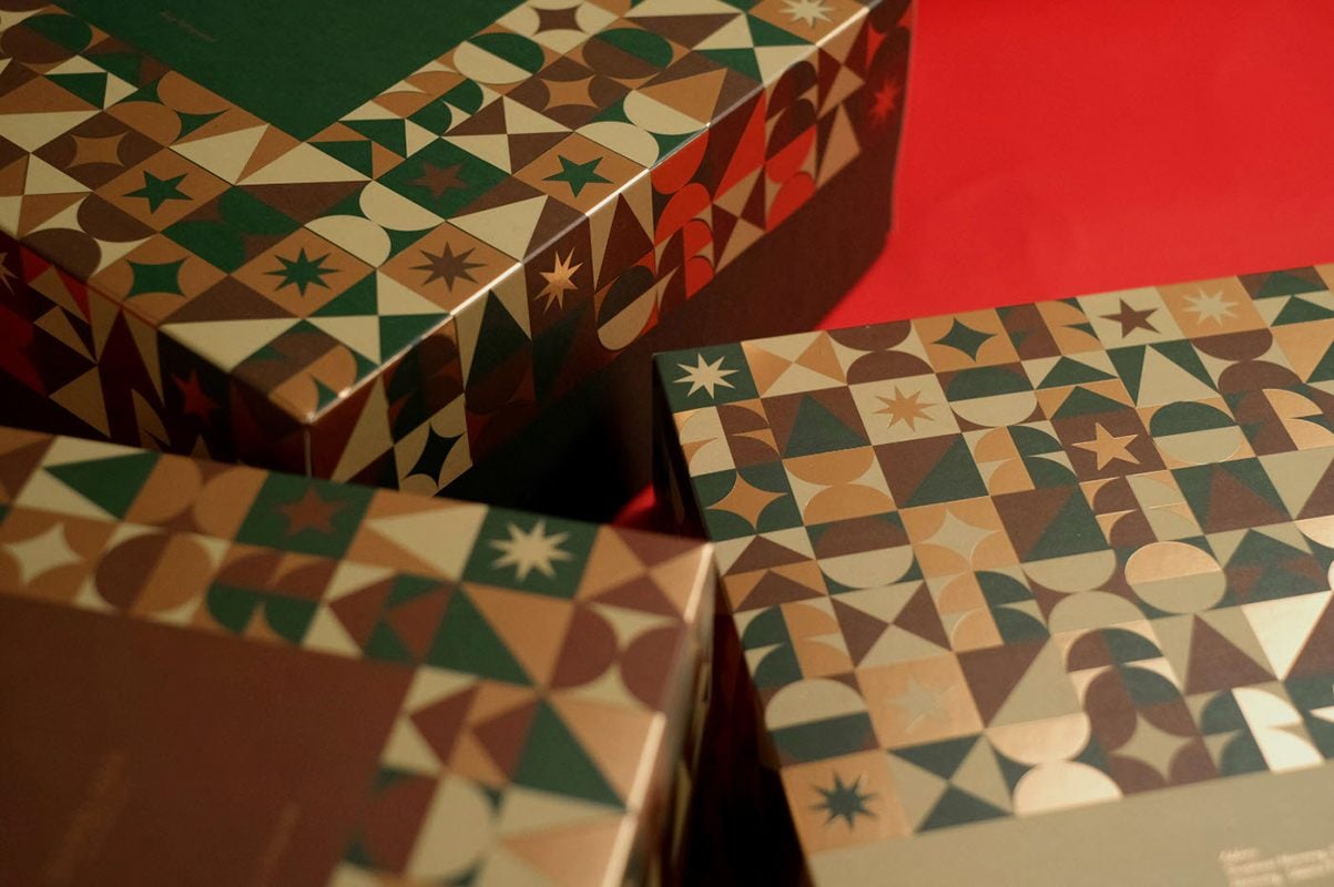 A close-up shot of three holiday packaging boxes on a red background.> <figcaption class=