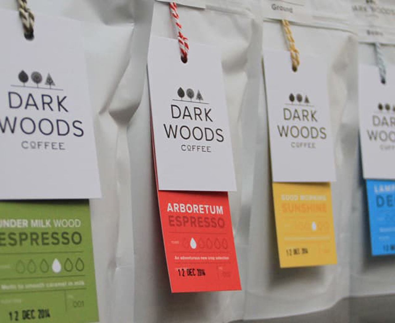 Different colored hang tag examples for the same brand hanged on simple white coffee bags.