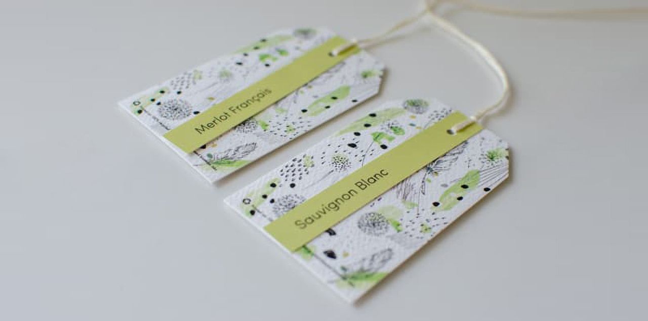 Hang tag examples for making your wedding wines unique with floral design on the white background and wine name written on the green stripe.