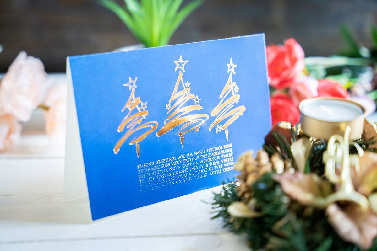 Holiday card design with gold foil details, folded holiday card on a wooden background.