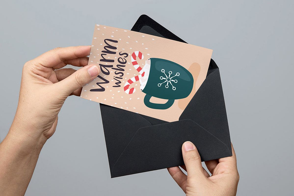 Hands holding a black envelope and a holiday card.