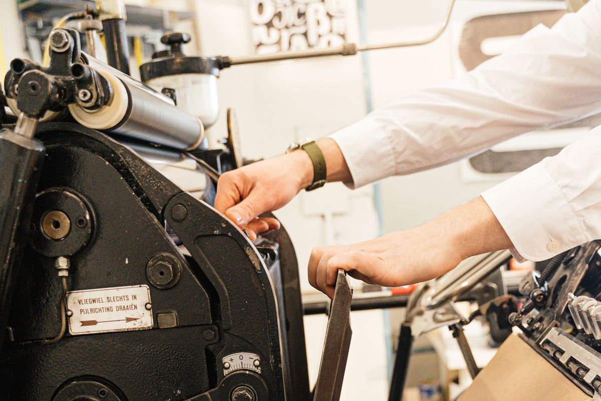 Closeup shot of an print machine operator adjusting a printing machine.