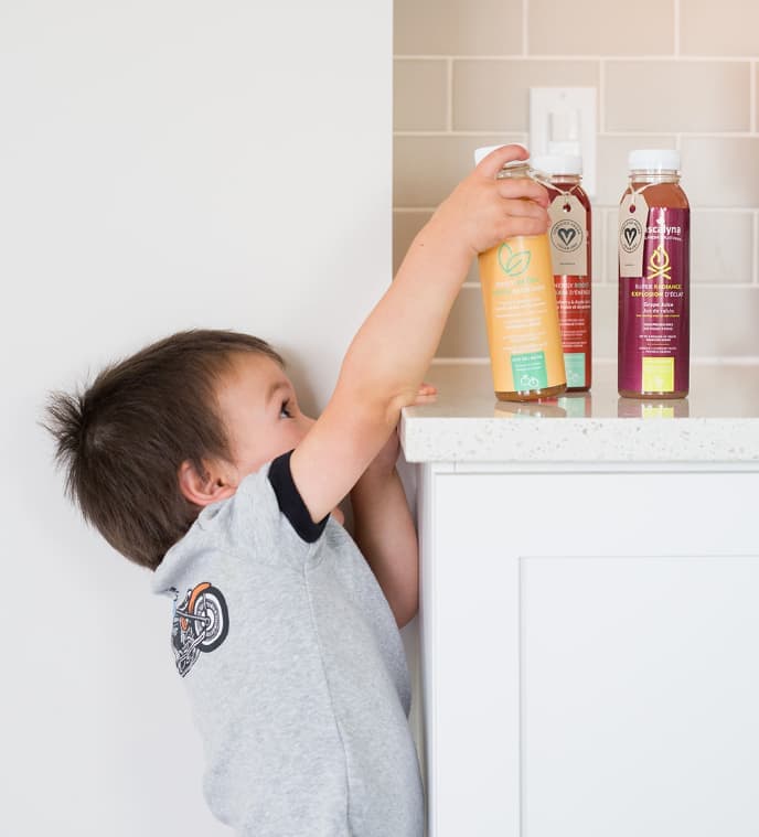 Image of a child taking bottle with distinctive label for juice bottles from a kitchen surface.
