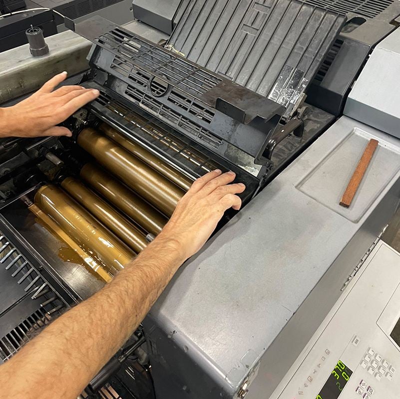 Spot color vs CMYK, a print operator adjusting the cylinders in a printing machine.